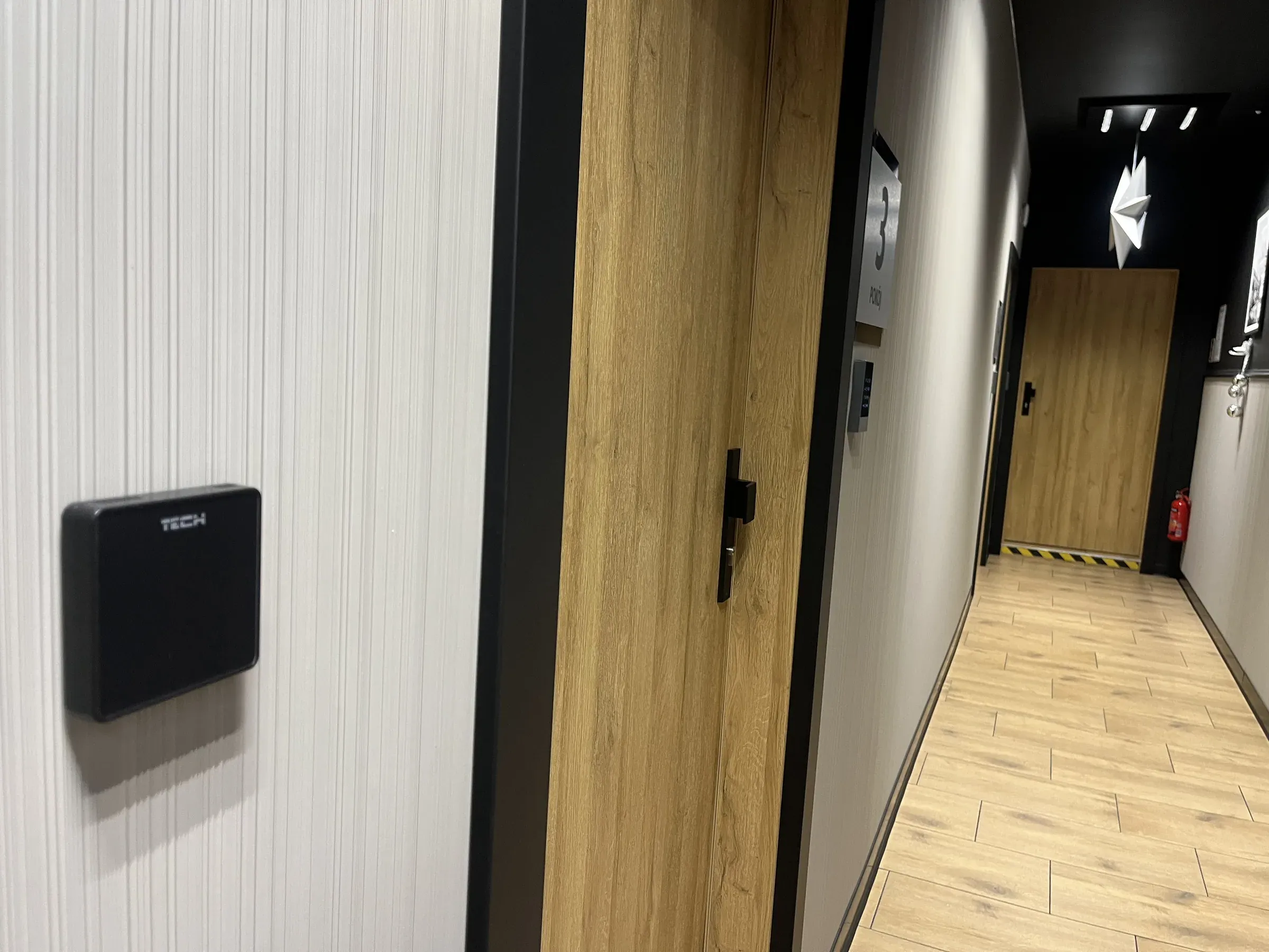 Regulator TECH na korytarzu hotelu — część wspólna jako osobna strefa